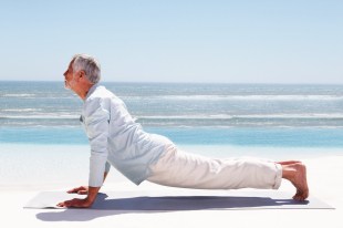 Photo of an attractive fresh senior mature man exercising on the beach